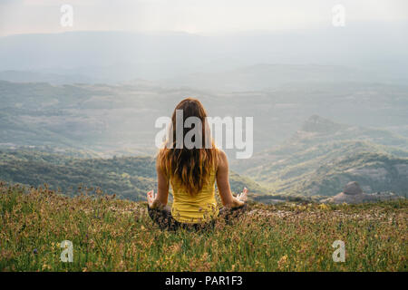 Spain, Barcelona, back view of young woman practising yoga on Montcau Mountain Stock Photo