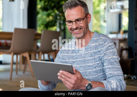 Smiling mature man at home using a tablet Stock Photo