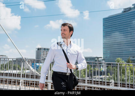 Smiling businessman walking on a bridge Stock Photo