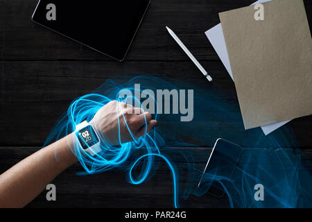 Man wearing smartwatch in office, connecting to portable devices Stock Photo