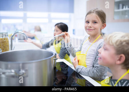 Portrait of smiling schoolgirl with classmtes in cooking class Stock Photo