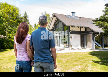 Couple standing hand in hand in garden of their home Stock Photo