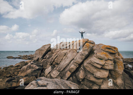 France, Brittany, Meneham, man standing on rock formation at the coast Stock Photo
