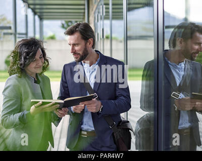 Colleagues with book talking outside office building Stock Photo