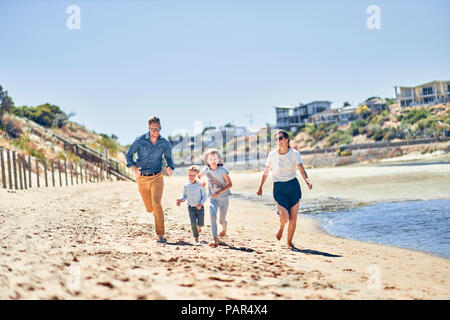 Australia, Adelaide, Onkaparinga River, happy family running on the beach together Stock Photo