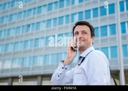 Smiling businessman on cell phone in the city Stock Photo