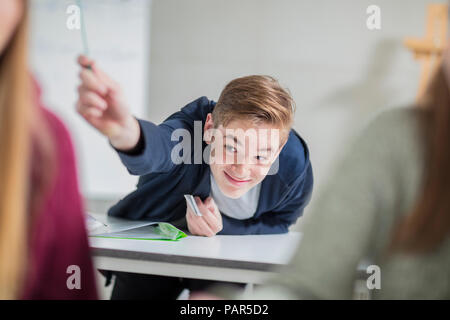 Smiling teenage boy passing a note in class Stock Photo