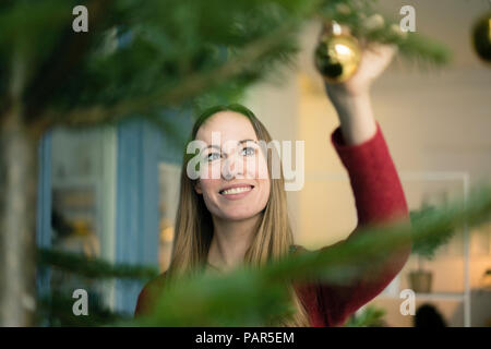 Portrait of smiling woman decorating Christmas tree Stock Photo