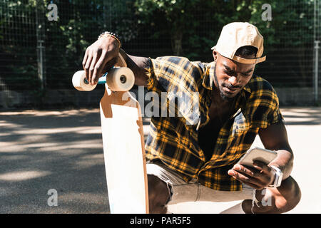 Cool young man in skate park, using smartphone Stock Photo