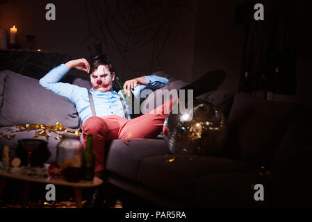 Man in Halloween costume sleeping on couch after party Stock Photo