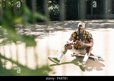 Cool young man in skate park, using smartphone Stock Photo