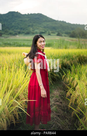 Girl in a rice field wearing red dress and a hat Stock Photo