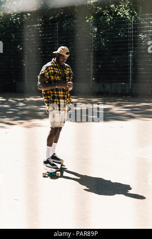 Cool young man in skate park, using smartphone Stock Photo
