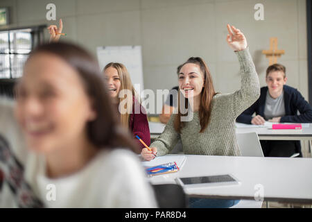 Happy teenage girls raising hands in class Stock Photo