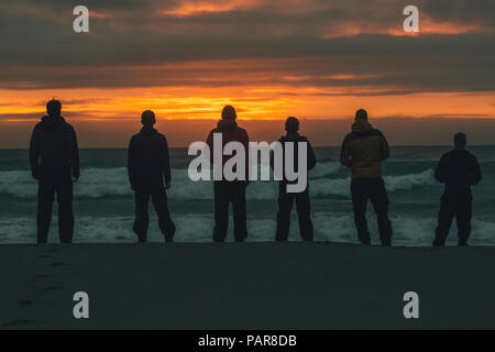 Norway, Lofoten, Moskenesoy, Young men standing at Bunes Beach at sunset Stock Photo