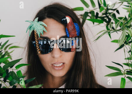 Young woman wearing exotic sunglasses with palm tree and parrot Stock Photo