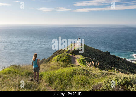 Woman stands in front of lighthouse at Cape Reinga, Northland, North Island, New Zealand Stock Photo