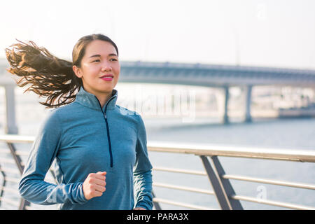 Girl running by the river in a modern city environment Stock Photo
