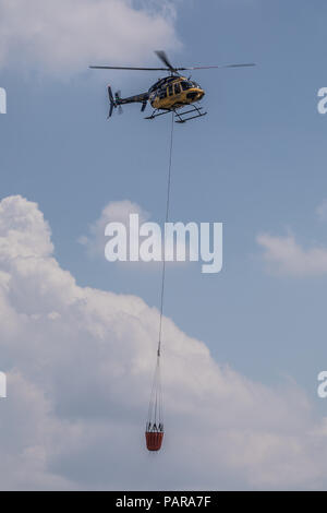 Helicopter with water tank for fire extinguishing, Switzerland Stock Photo