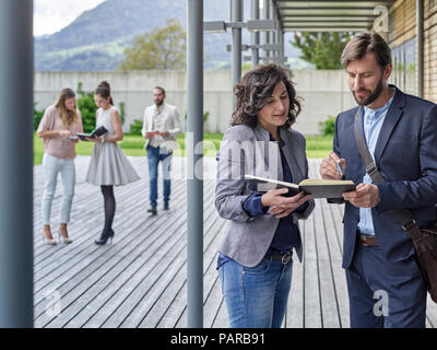 Colleagues with book talking outside office building Stock Photo