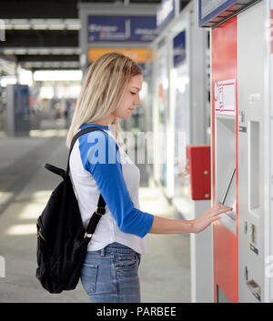 Blond woman using ticket machine at train station