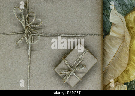 Composition of gift boxes wrapped in beige paper and bundled with ribbons. Decorated with dry leaves Stock Photo