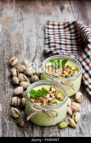 Natural  pistachio yogurt in a small glass jar on wooden table Stock Photo