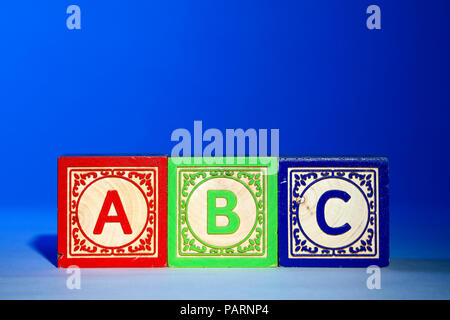 Wooden letter blocks on a blue background with the letters abc Stock Photo