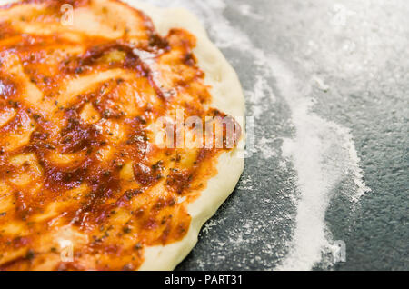 Preparing pizza, close-up of pizza dough with tomato sauce. Stock Photo