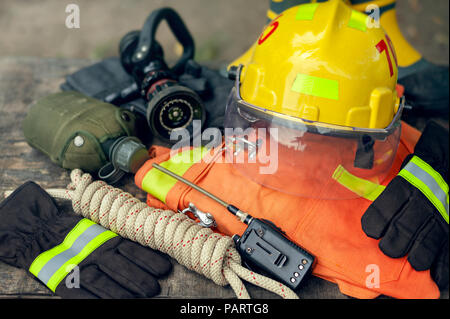 Outfit of Firefighter placed on wooden table background, Fire equipment concept. Stock Photo