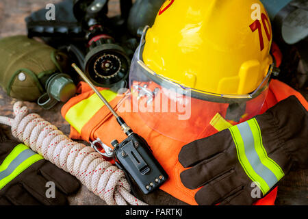 Outfit of Firefighter placed on wooden table background, Fire equipment concept. Stock Photo