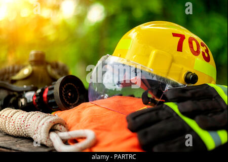 Outfit of Firefighter placed on wooden table background, Fire equipment concept. Stock Photo