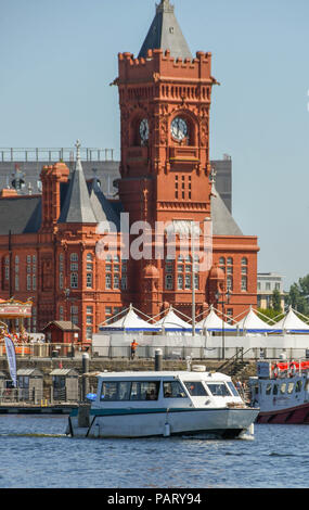 Small water taxi taking passengers across Cardiff Bay passing the landmark Pierhead Building Stock Photo