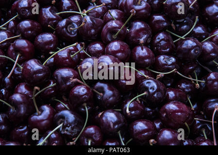 A large amount of fresh cherries in a food market. A pile of cherries. Cherries wallpaper. Fruit wallpaper. Stock Photo