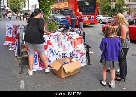 Mum & children  street scene stall in shopping high street buying England football team souvenir on day of World Cup game Brentwood Essex England UK Stock Photo