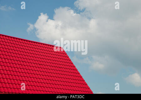 red metal tile roof in front of blue sky background Stock Photo
