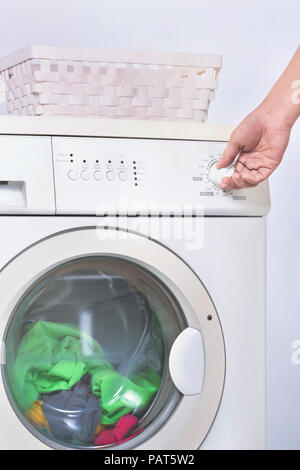 Male hand setting the program on washing machine. Home appliance Stock Photo