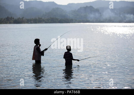 Papua New Guinea, Vanimo, silhouette of mother and child fishing in water. Stock Photo
