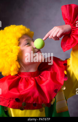 cheerful little clown touches own fake nose Stock Photo