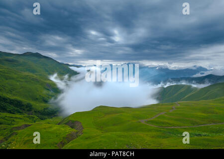 Mountain view from Datvijvari (Bear Cross) pass with heavy fog rising up from the valley under troubled sky before storm, Khevsureti, Georgia Stock Photo