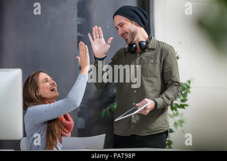 Two colleagues giving high five in meeting. Business people celebrating ...