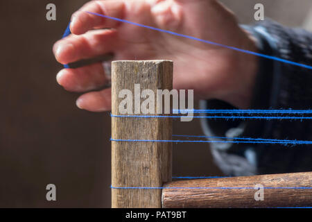 Thread on a loom with a hand in the background. Stock Photo