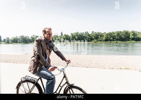 Mature man with bike at Rhine riverbank Stock Photo