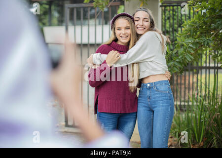 Teenage girl taking a picture of her happy friends outdoors Stock Photo