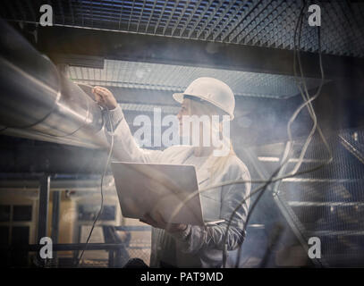 Female technician working on pipeworks, using laptop Stock Photo