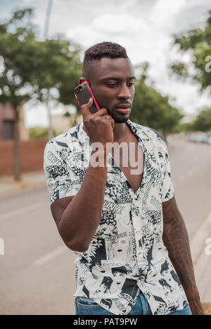 Young man in the city, standing in the street, talking on the phone Stock Photo