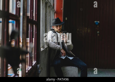 Bearded man wearing black hat, using smartphone Stock Photo