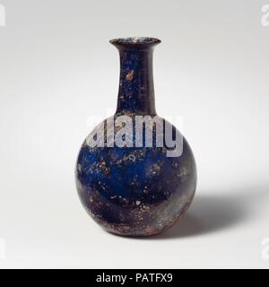 Glass perfume bottle. Culture: Roman. Dimensions: Height: 3 1/8 in. (8 cm)  Diameter: 2 1/16 x 7/8 in. (5.2 x 2.2 cm). Date: 1st century A.D..  Translucent deep cobalt blue.  Uneven, rounded rim; short, flaring mouth; cylindrical neck, expanding downwards; globular body; small, concave bottom.  Intact; some pinprick and larger bubbles; patches of dulling and iridescent weathering. Museum: Metropolitan Museum of Art, New York, USA. Stock Photo