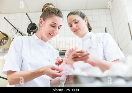 Women in pastry bakery glazing cupcakes Stock Photo