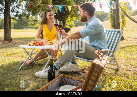 Beautiful couple in love toasting with red wine during romantic picnic Stock Photo